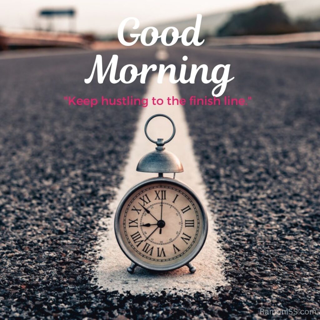 In the photo, an alarm clock is placed in the middle of a road and it is 9:53 am on the clock, in the photo, good morning "keep hustling to the finish line" is also written.