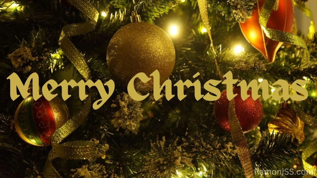 The photo shows christmas tree decorated with lights, christmas balls and ribbons, with the words merry christmas written using yellow stylish font.