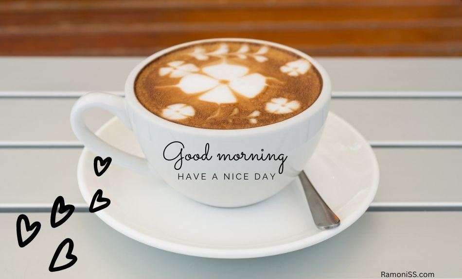 The photo placed a cup and spoon full of coffee on a plate on a white table, with the words good morning "have a nice day" written on the cup