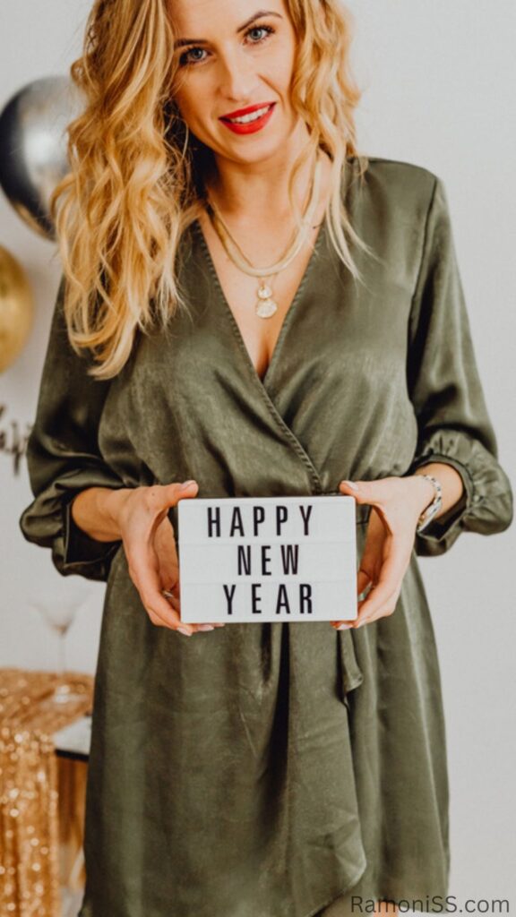 Happy new year 2023 card image template in black font, room decorated with the help of yellow and silver color balloons and happy new year card in the hands of beautiful lady.
