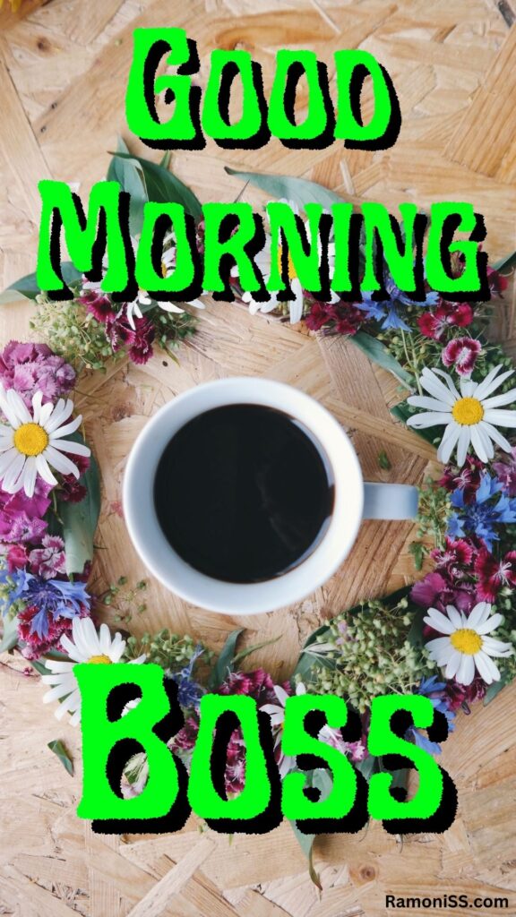Good morning boss is written in the image and in the background image a cup of black tea is placed on a wooden table decorated with flowers.
