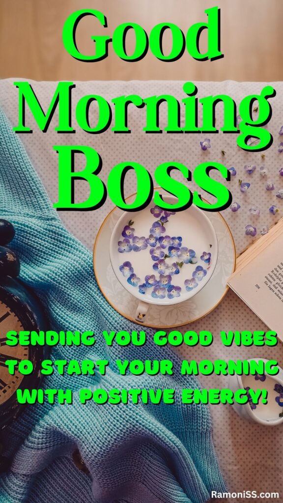 Good morning boss is written in the image and in the background image sweater, alarm clock, book, and cup of milk are placed on the wooden table.