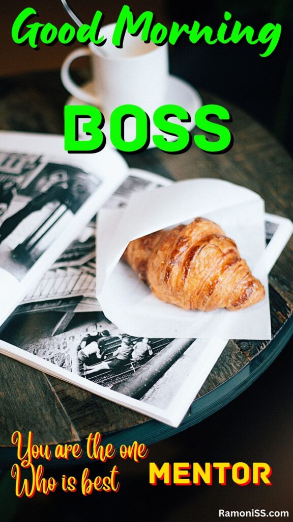 Good morning boss written in the image and in the background image a cup of tea, a spoon, two pieces of cookie, and an album of photos are placed on a table.