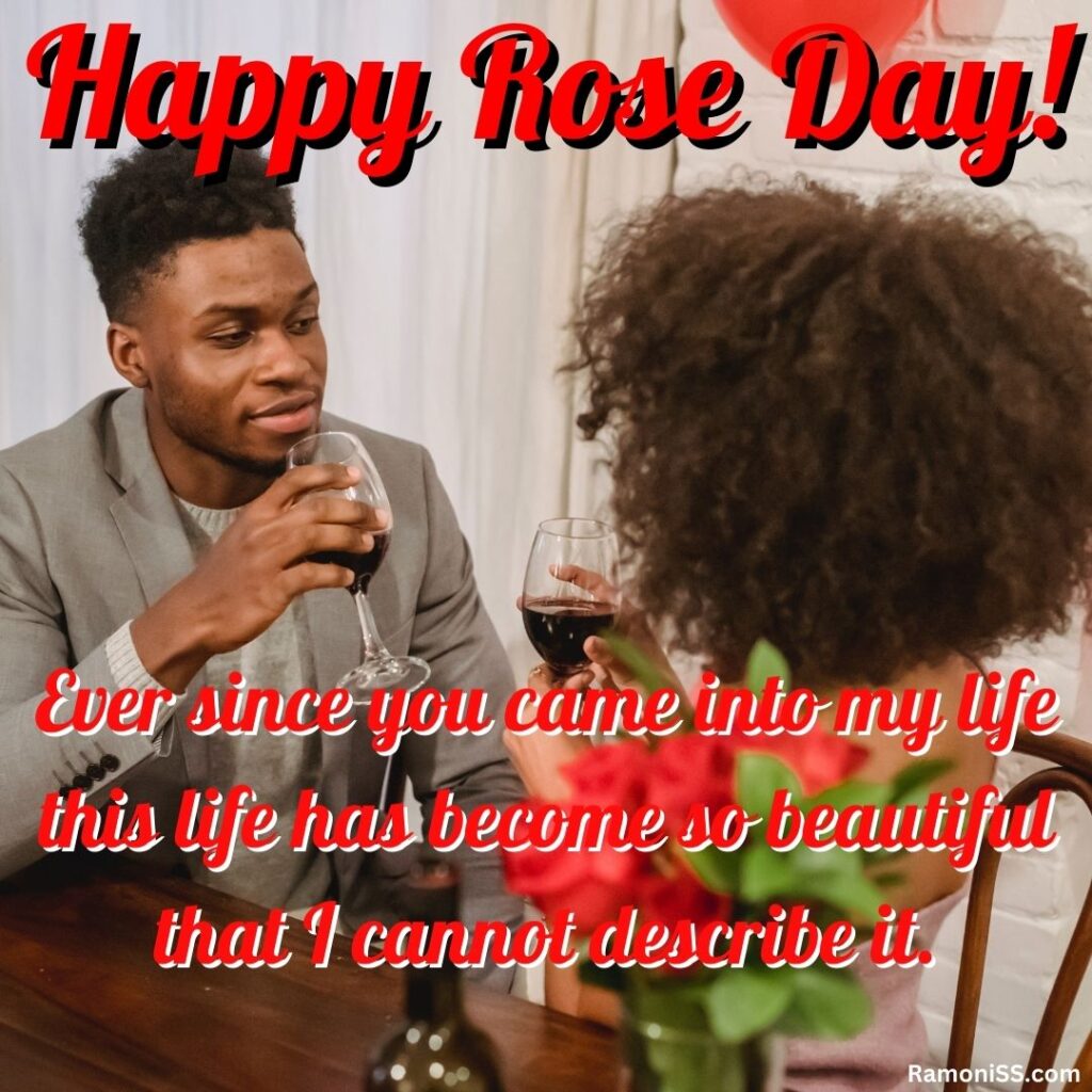 Curly hair girl sitting with her curly hair boyfriend celebrating rose day with a drink, and roses placed on the wooden table.