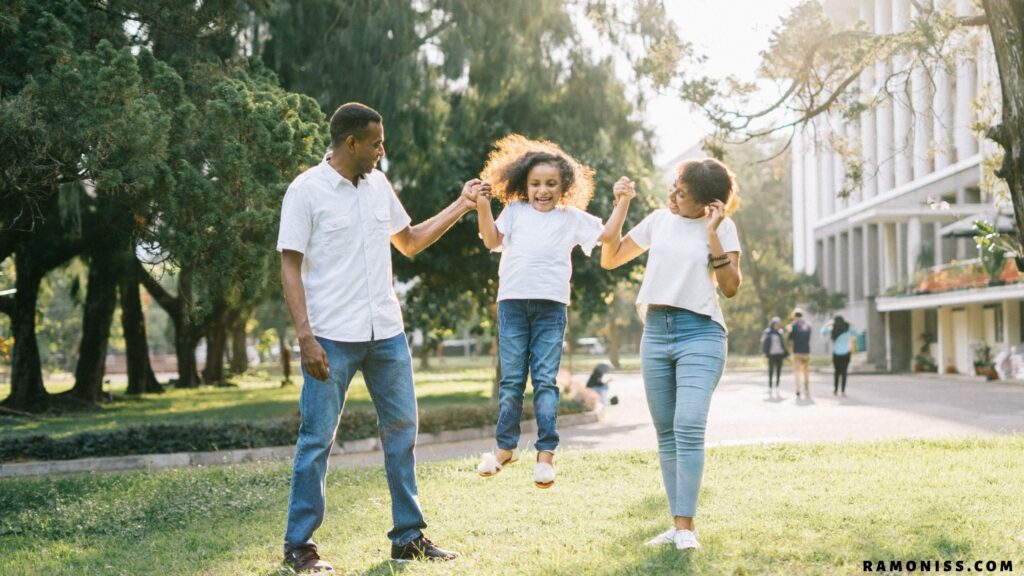 In the photo, a happy mother and father lift their daughter off the ground by both hands