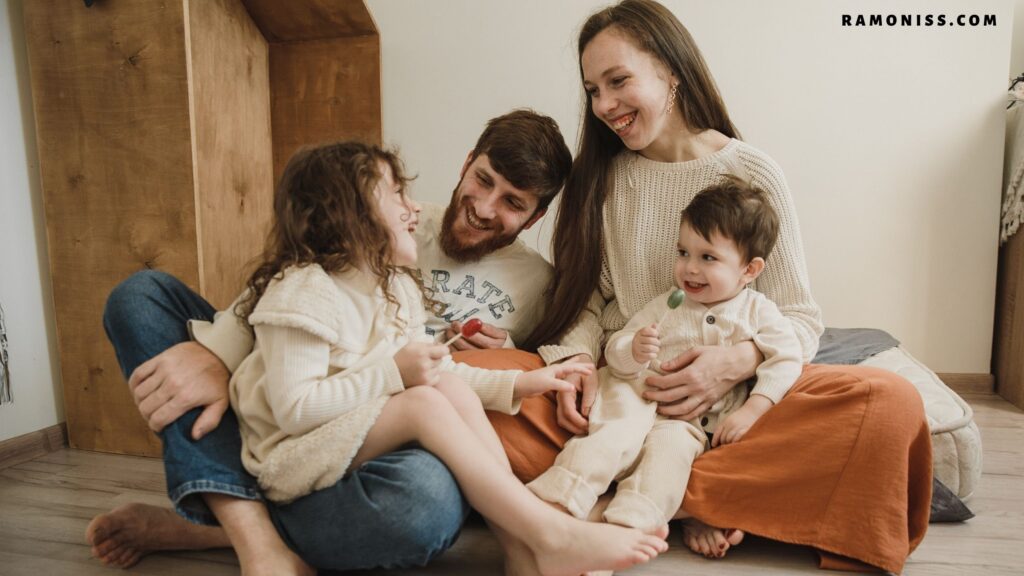 In the picture, the parents are laughing with their daughter and son sitting on the mattress in the room.