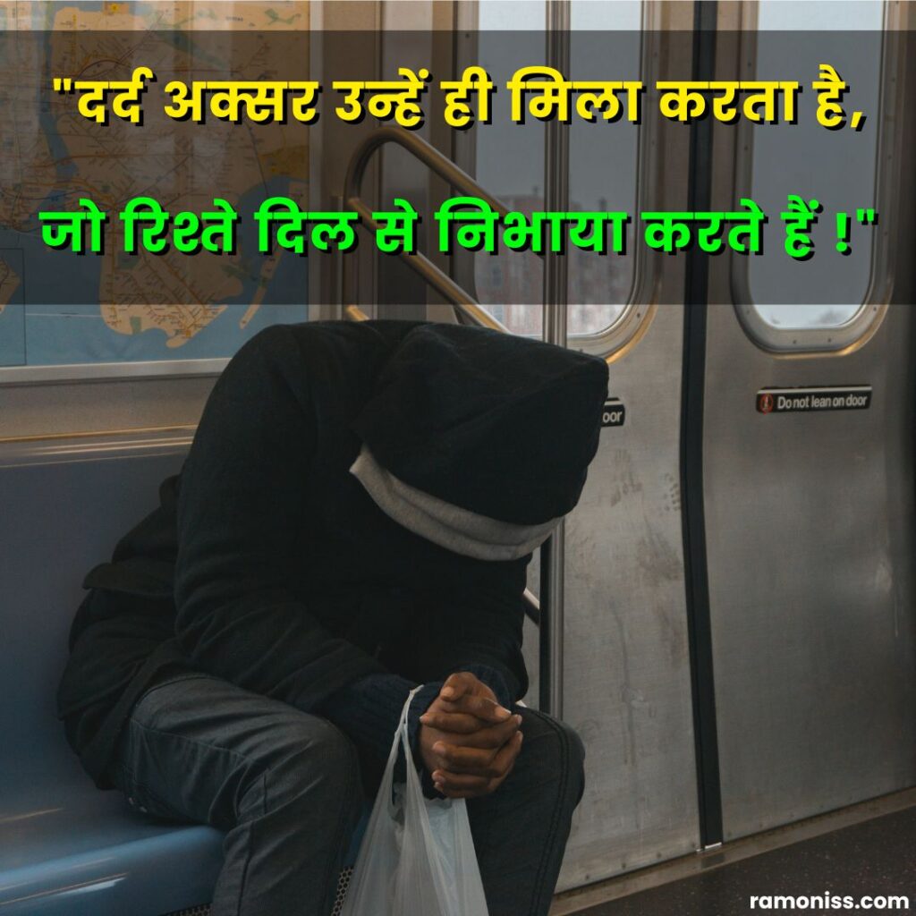 In the picture, a sad boy in a black hoodie with his head bowed is sitting on a train bench and sad shayari quotes are also written.