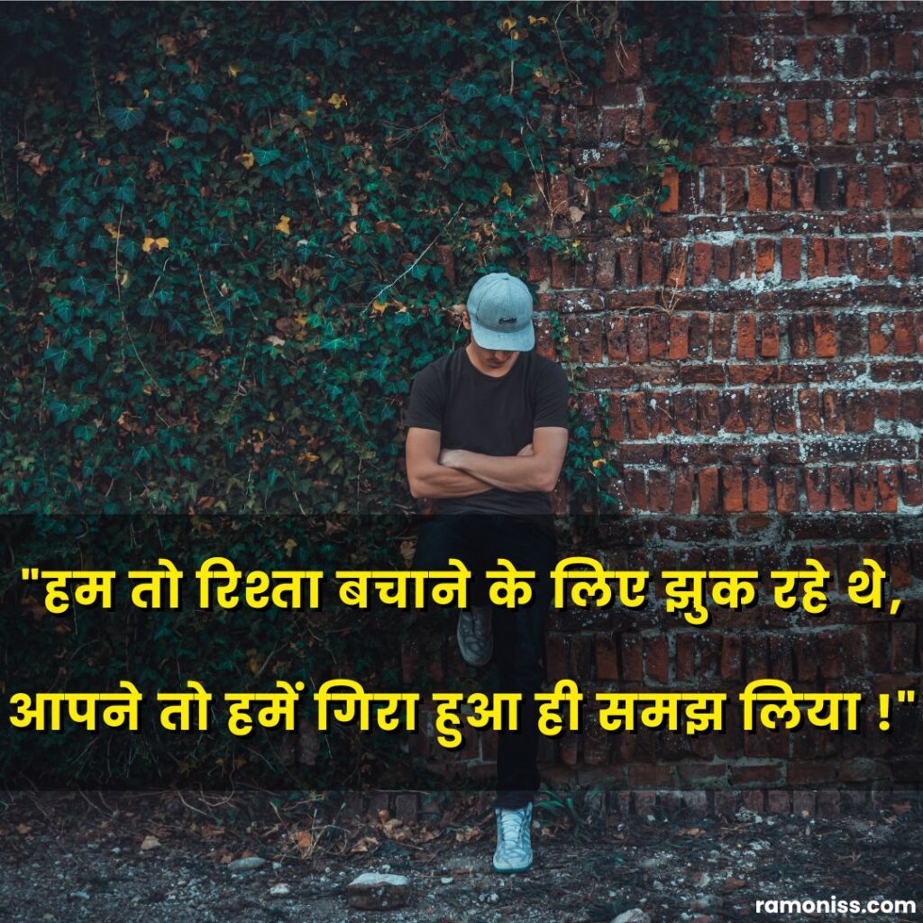 In the image, sad boy wearing a cap and standing leaning against the wall with his head bowed and sad quotes in hindi are also written.